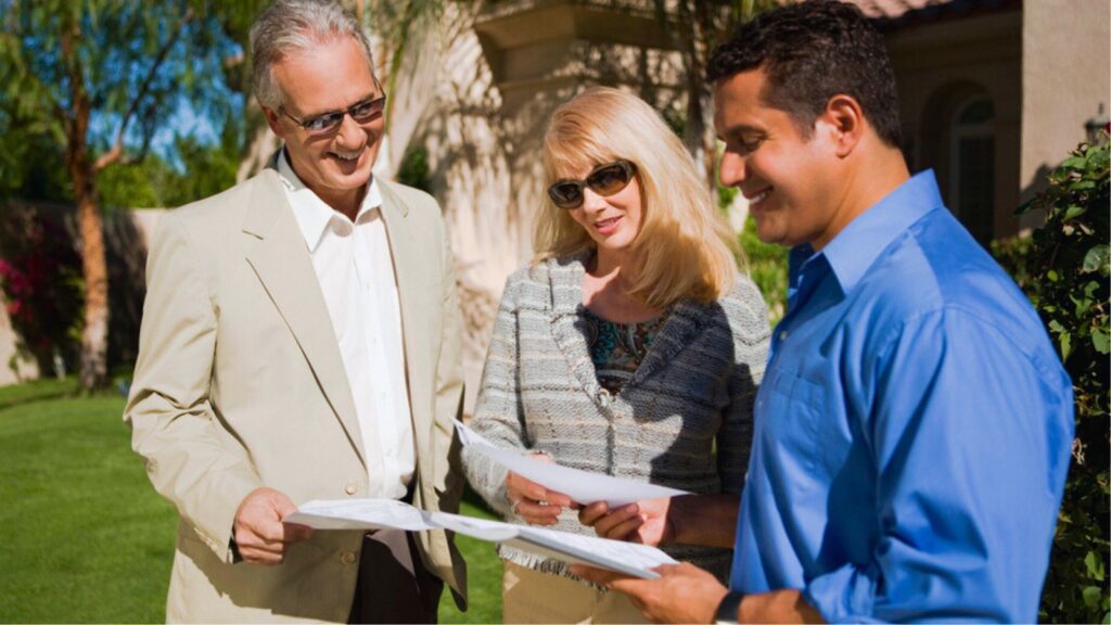 Happy couple with real estate agent discussing paperwork