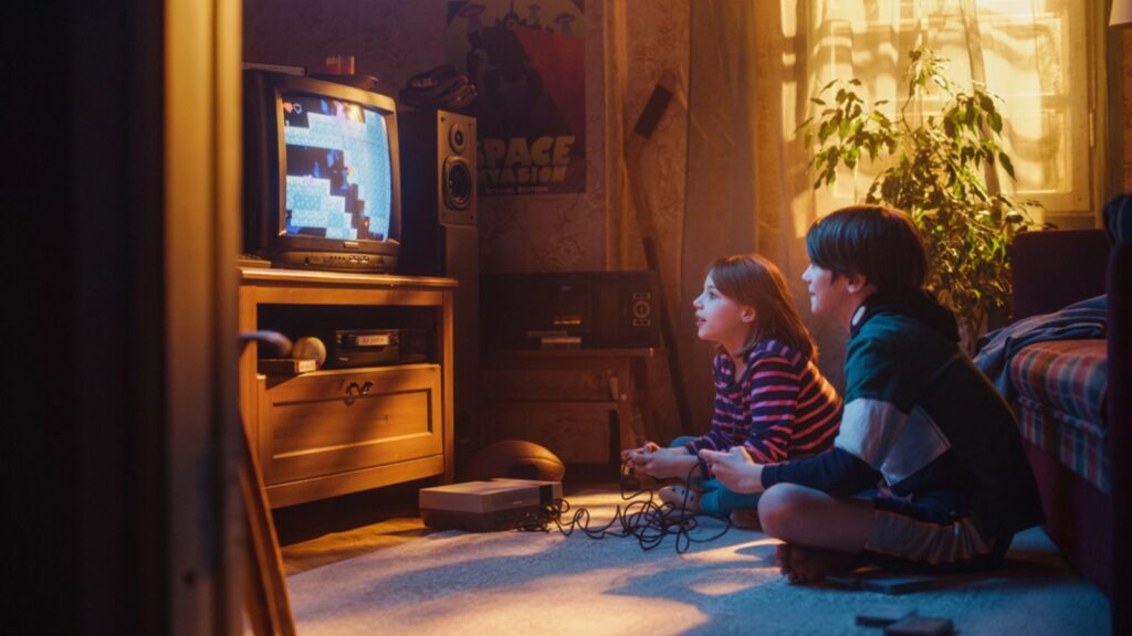 Nostalgic and Happy Childhood Concept Young Brother and Sister Playing 8 Bit 2D Arcade Video Game on a Retro TV Set at Home in a Room with Period