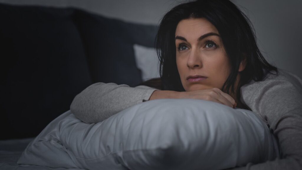 Selective focus of dissatisfied woman having insomnia while lying on bed at night