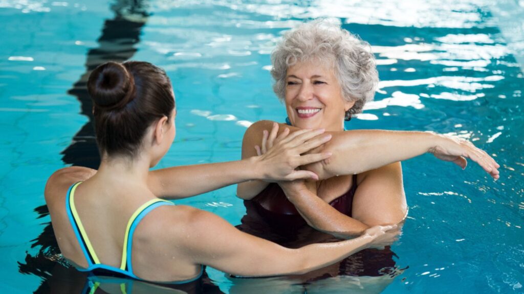 Senior woman stretching in pool