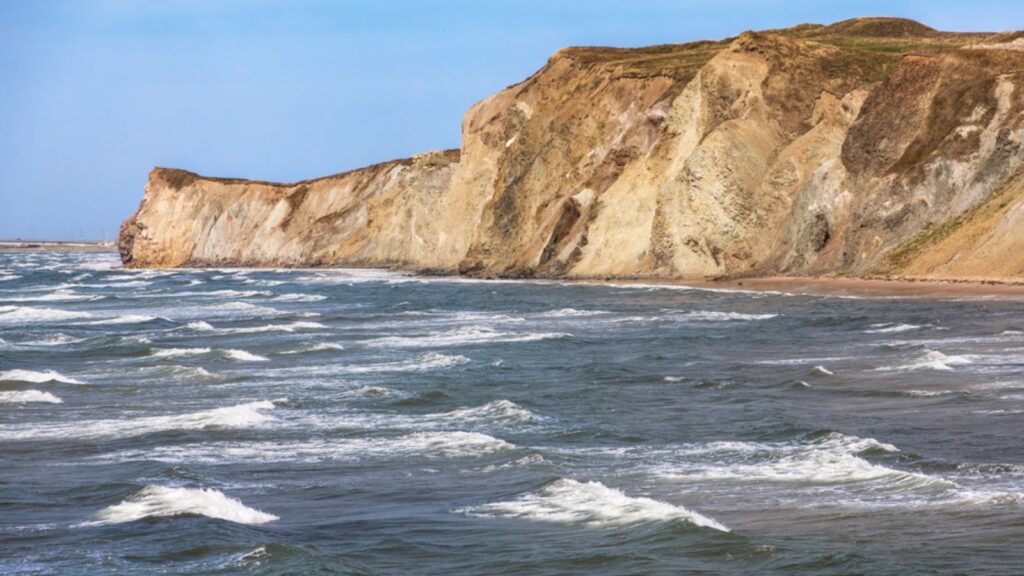 The colourful sandstone cliffs and choppy seas of Havre aux Maison, Magdalen Islands, Quebec Province, Canada