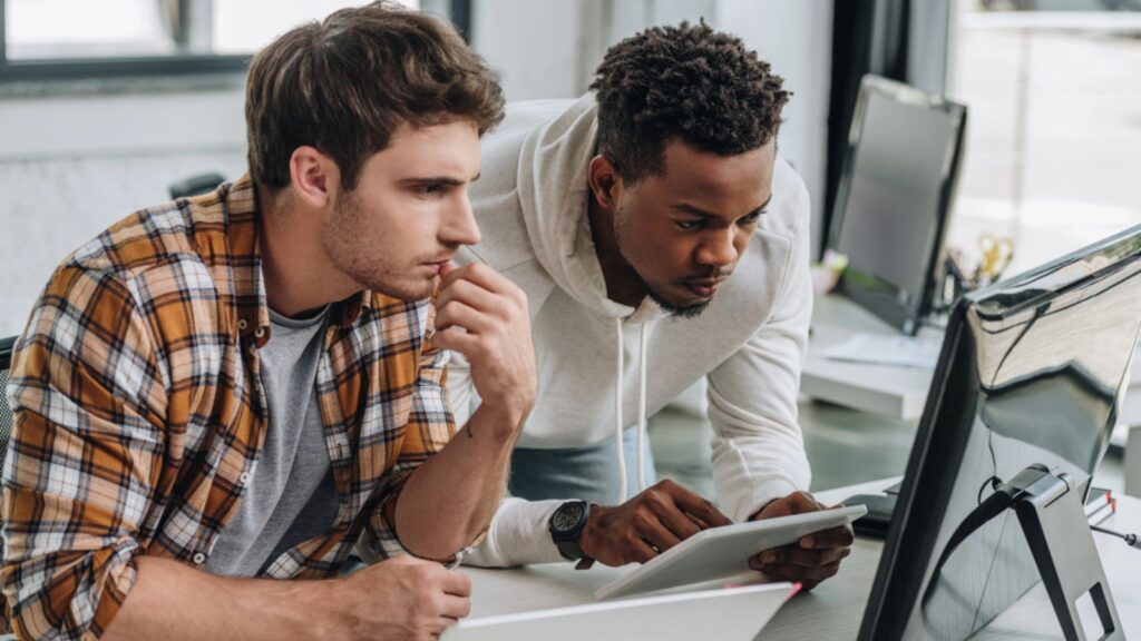 Two thoughtful multicultural programmers working at workplace together