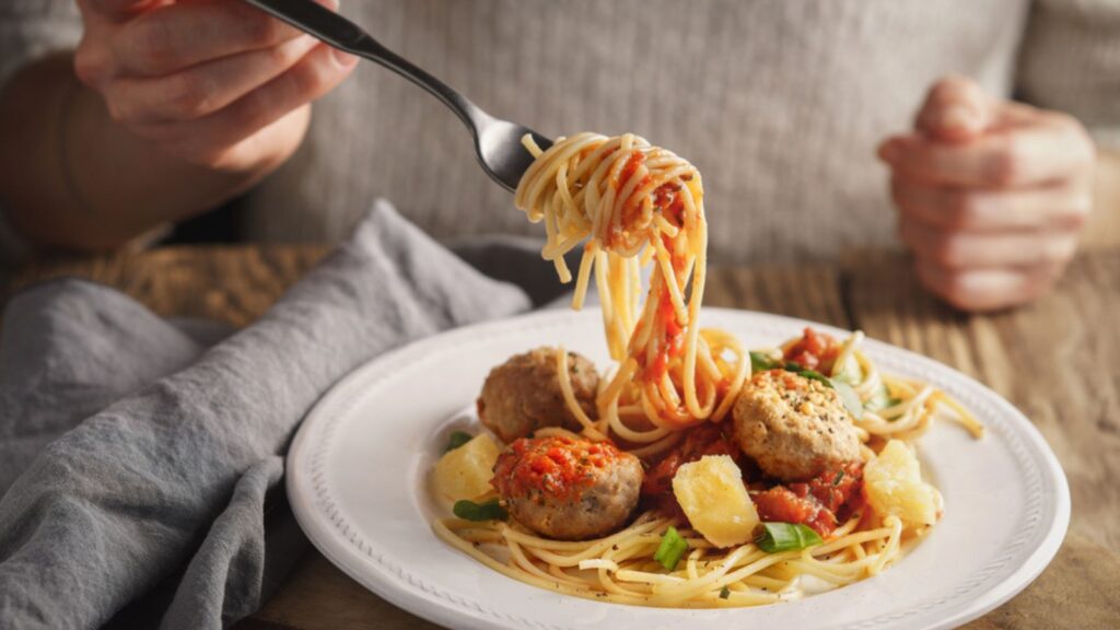 Woman eating spaghetti with meatballs and cheese