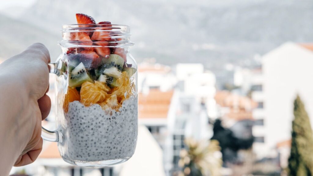 Woman hands with chia pudding, Strawberry, kiwi, orange served