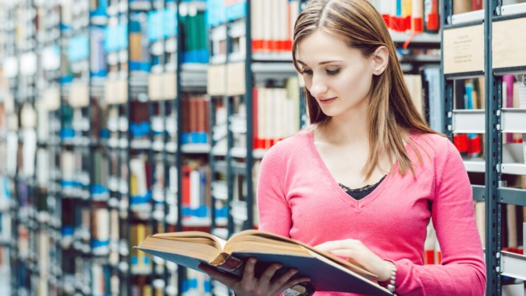 Woman in college library reading a book