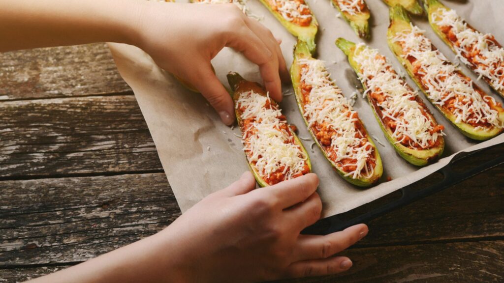 Woman sprinkles with cheese stuffed zucchini