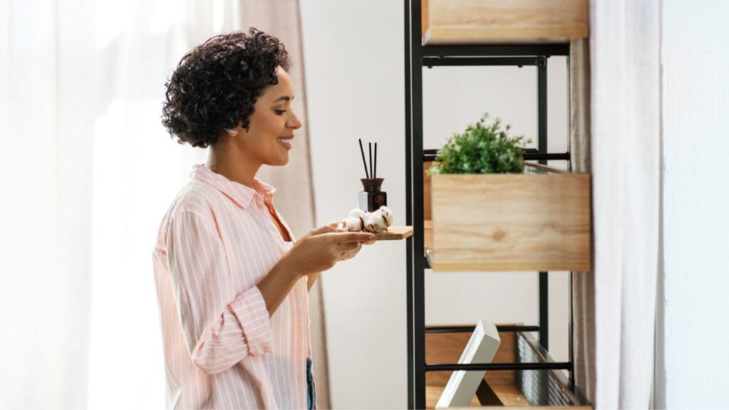 Woman with aroma reed diffuser and cotton at home