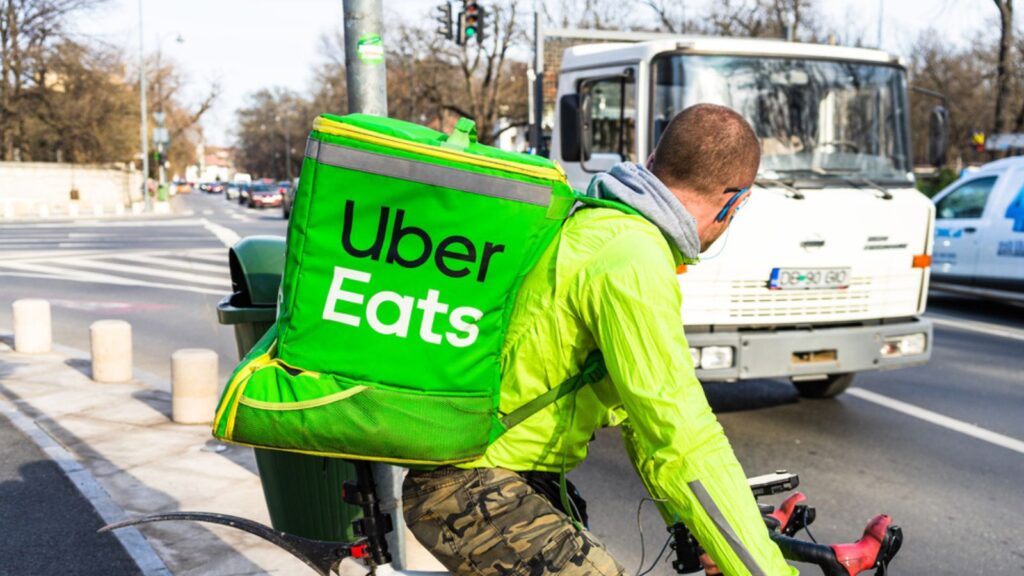 Young man on a bike with Uber Eats logo delivering food in Bucharest, Romania, 2020
