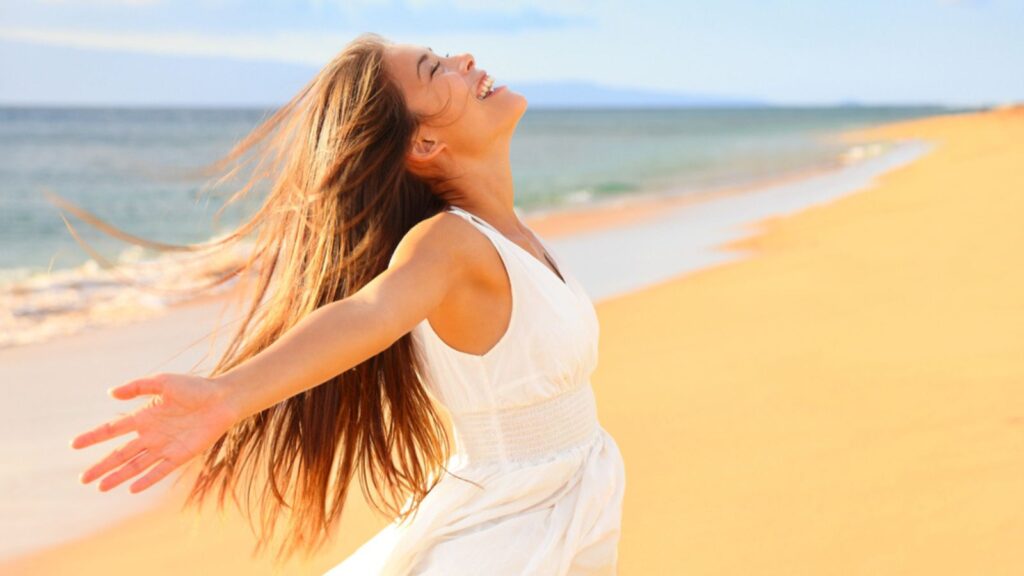 happy youthful excited woman on beach laughing dancing outside
