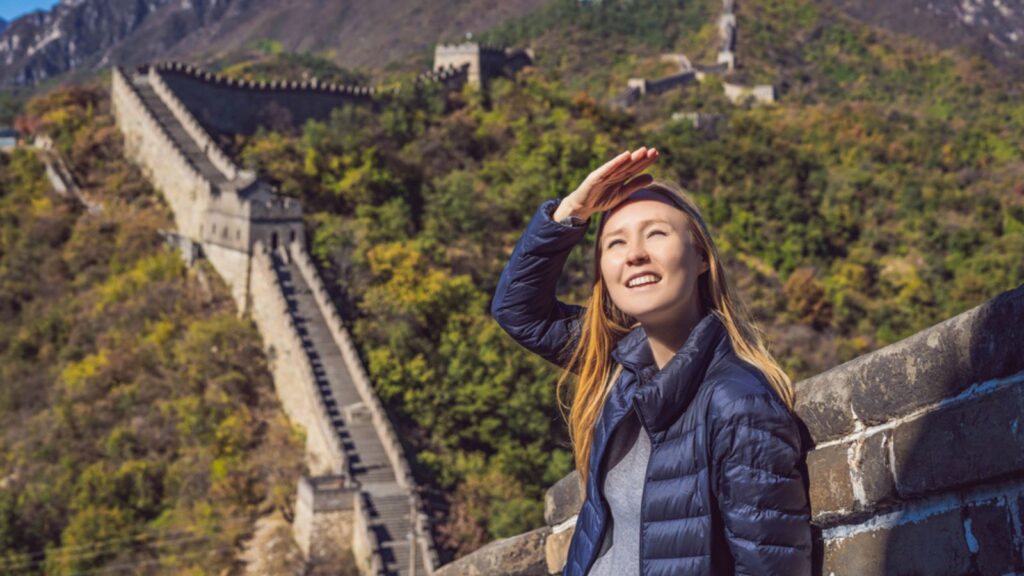 woman at Great Wall of China having fun on travel smiling laughing and dancing during vacation trip in Asia