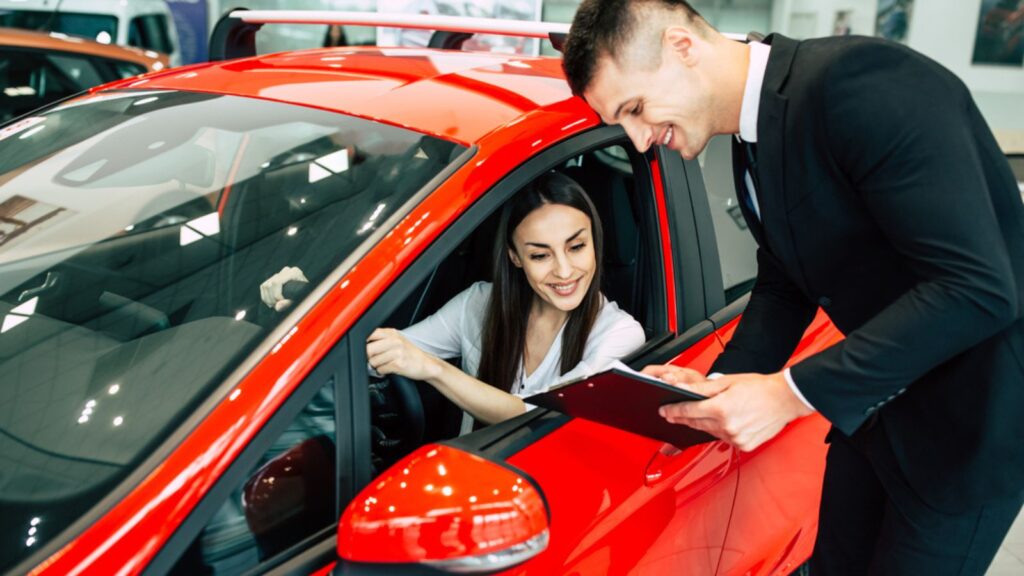 woman sitting in new car dealership talking to salesman