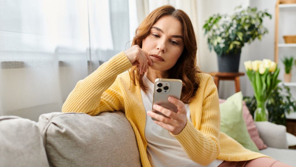 woman sitting on a couch, engrossed in her cell phone