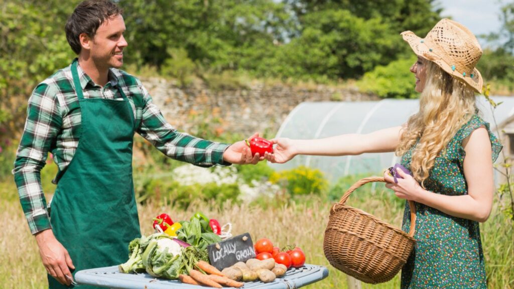 Beautiful woman buying vegetables at farmers stall