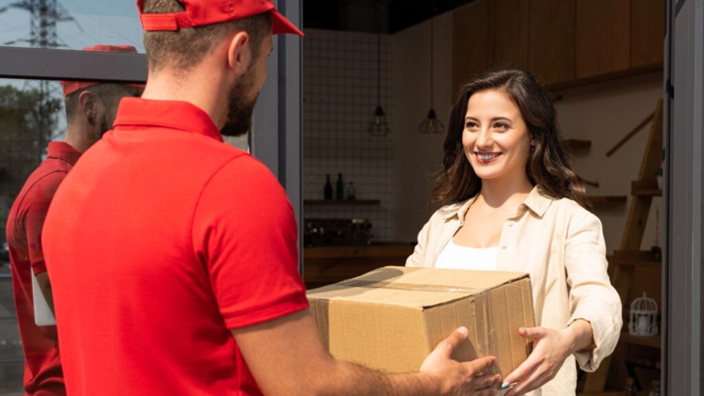 Delivery man giving cardboard box to happy woman