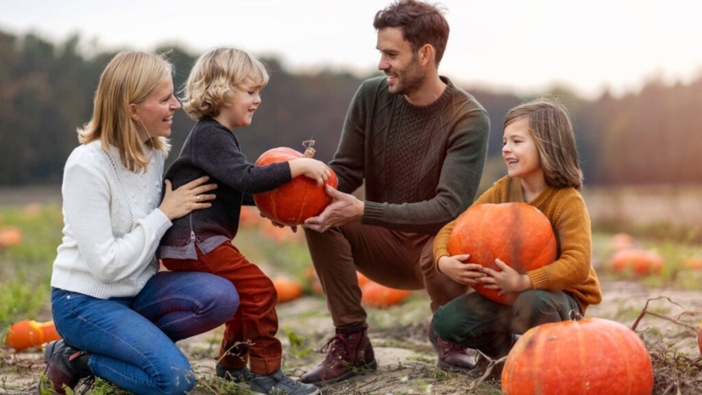 Happy young family in pumpkin patch field