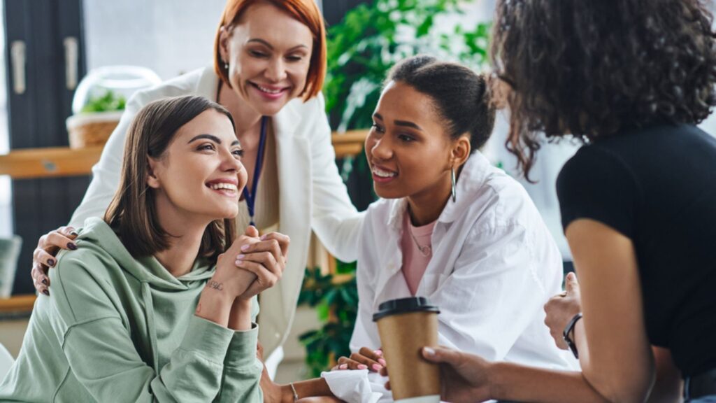Inspired and excited woman sitting and talking to multiethnic female friends