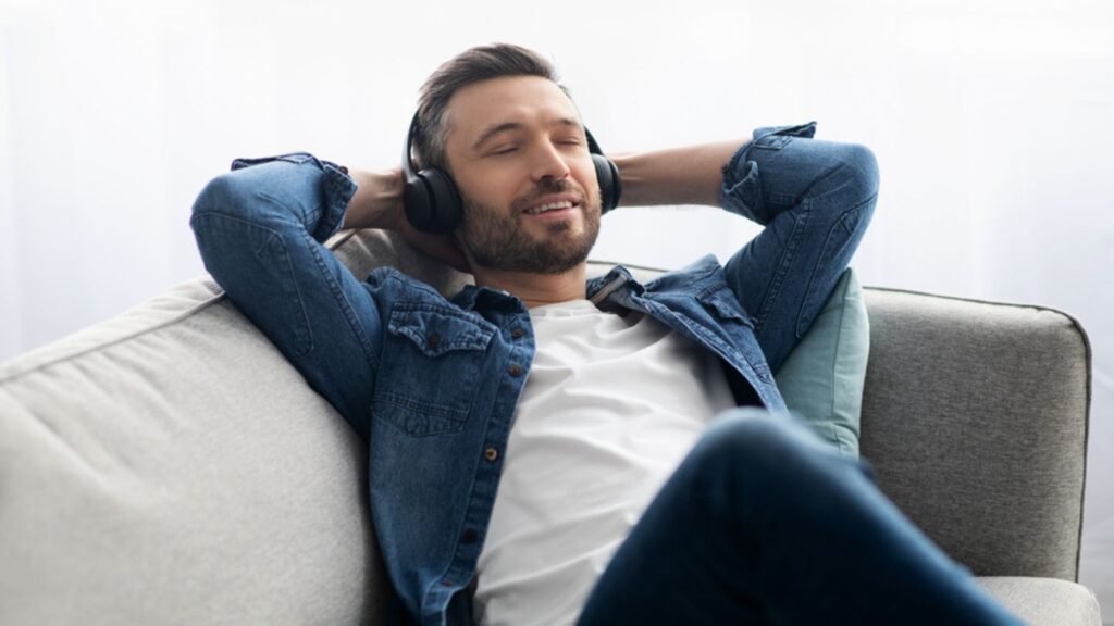 Joyful middle-aged man in headphones listening to music