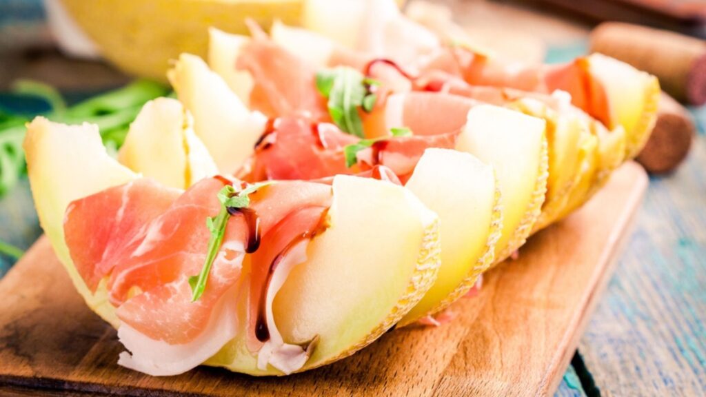 Melon with thin slices of prosciutto and arugula leaves
