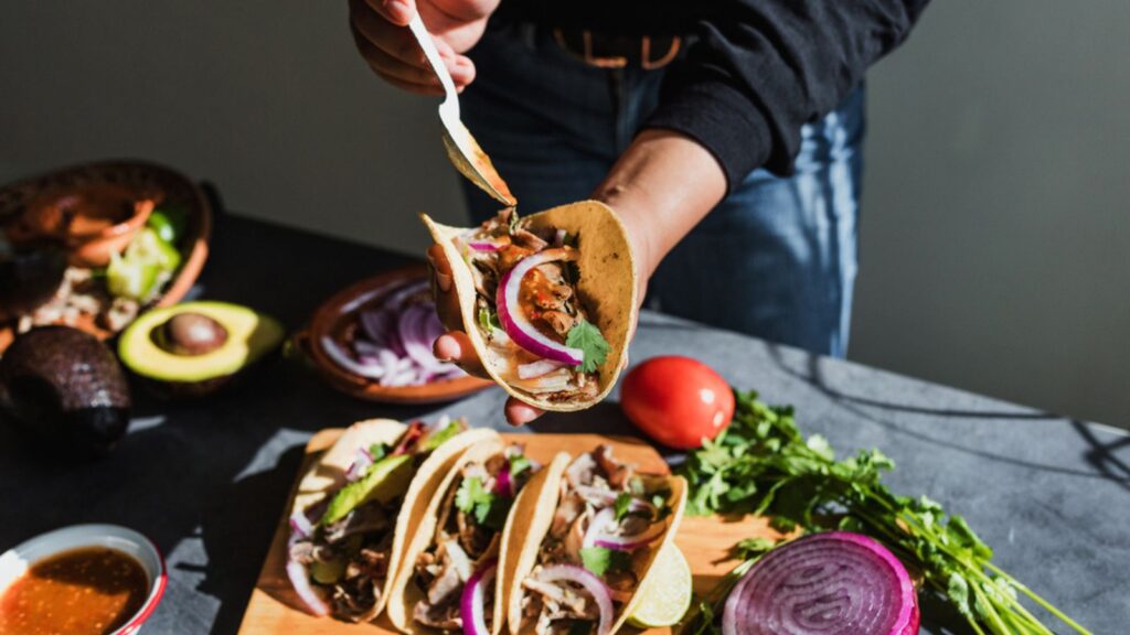 Mexican woman hands preparing tacos al pastor with sauce in Mexico city