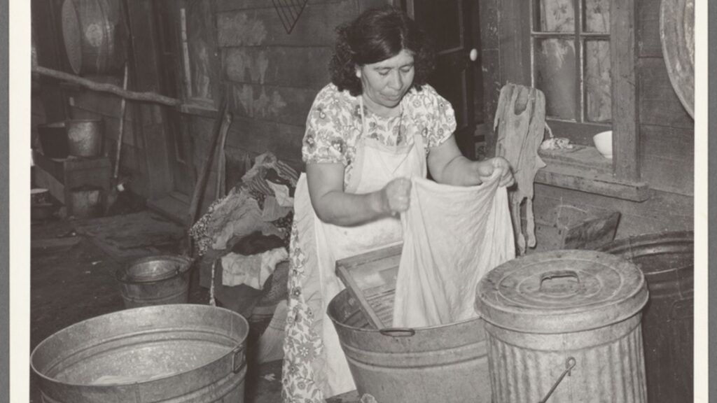 Mexican woman washing in front of house in corral. Mexican section, San Antonio, Texas