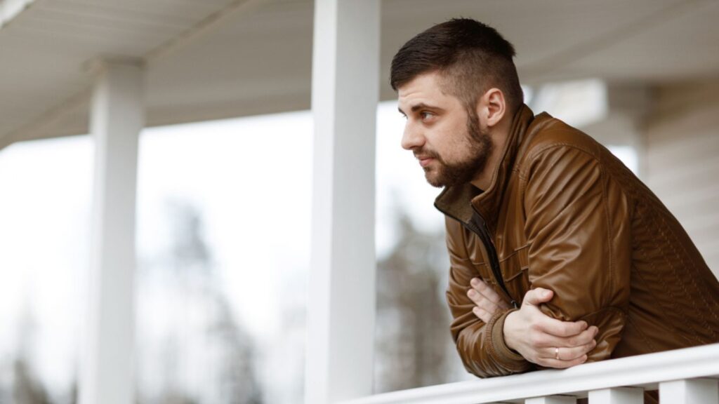Portrait of a sad and thinking man on the veranda of his house