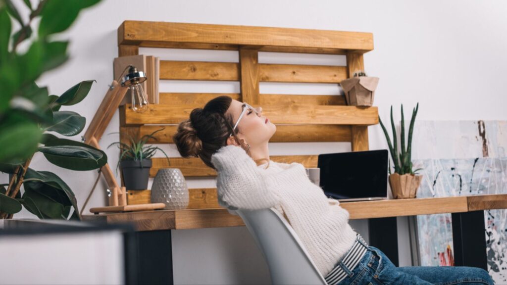 Side view of girl stretching on chair in office DIY Pallet