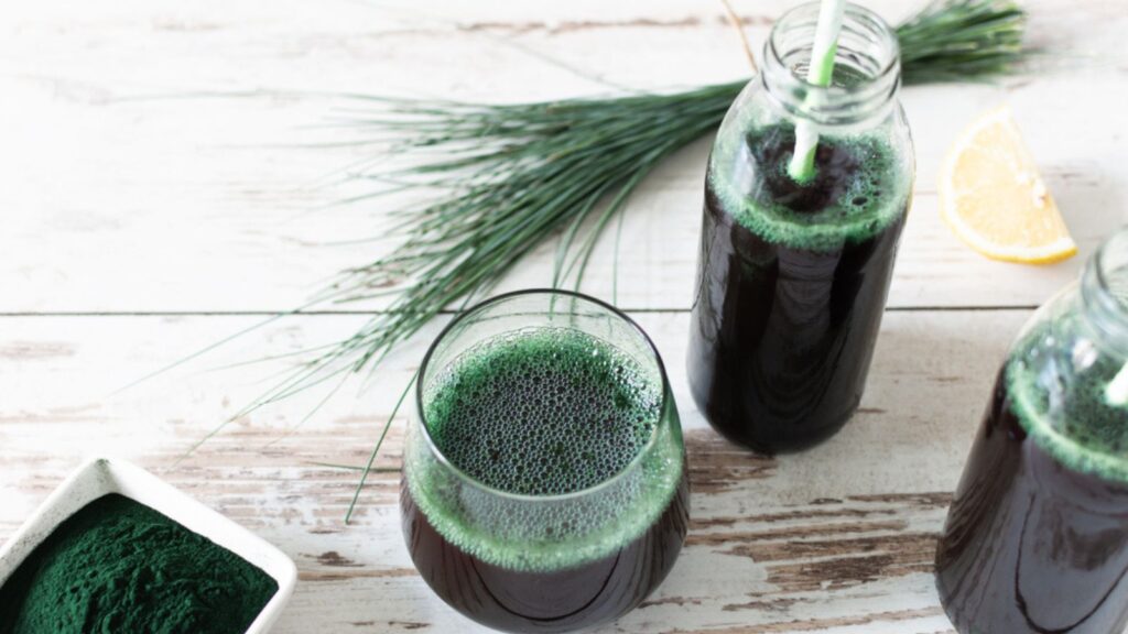 Spirulina drink and spirulina algae powder on white wooden table