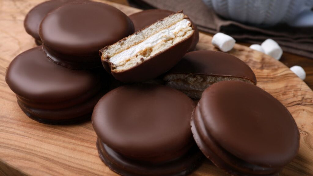 Tasty choco pies on wooden board, closeup view