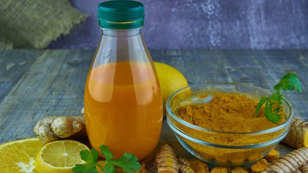 Turmeric juice in a bottle, ginger, lemon, orange and turmeric powder