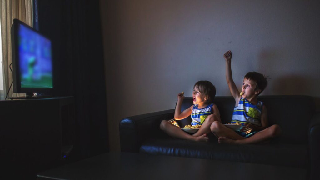 Children, sitting on the couch, watching TV at night at home