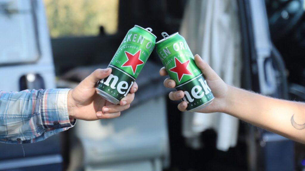 KHARKOV, UKRAINE - JULY 31, 2021 Green tin cans of Heineken pale lager beer in men hands outdoors