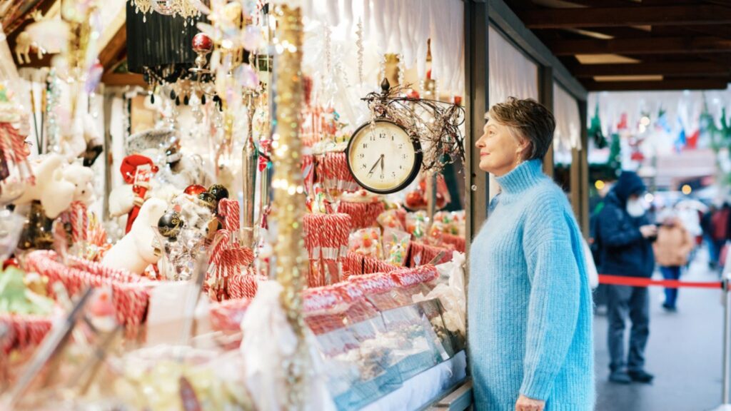 Outdoor portrait of beautiful middle age woman with grey hair buying gifts and souvenirs at Christmas market