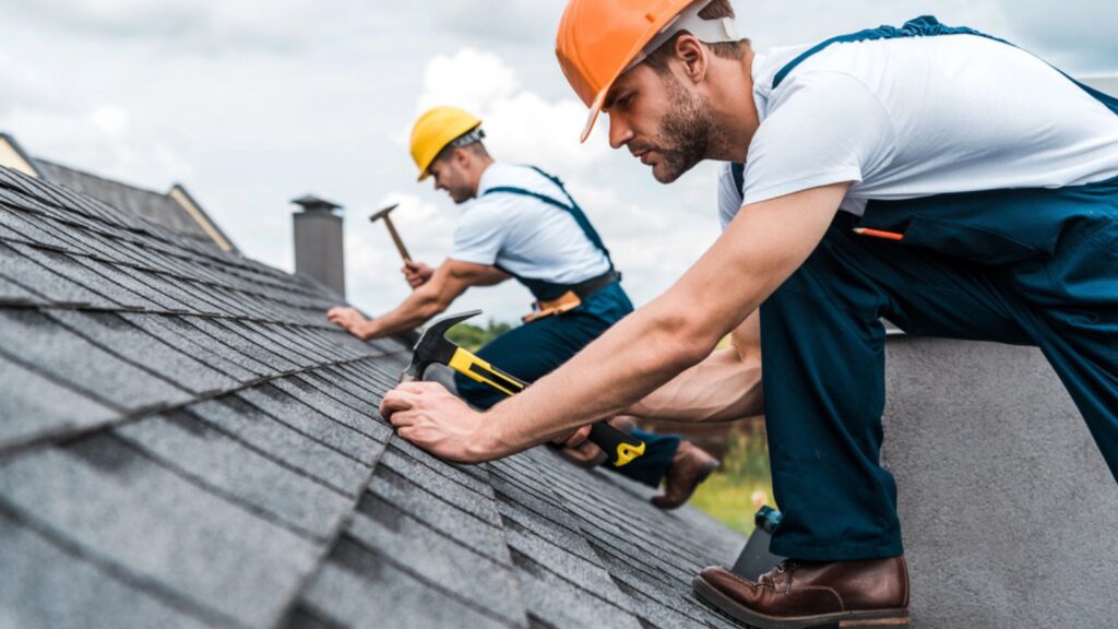 Selective focus of handsome handyman repairing roof with coworker