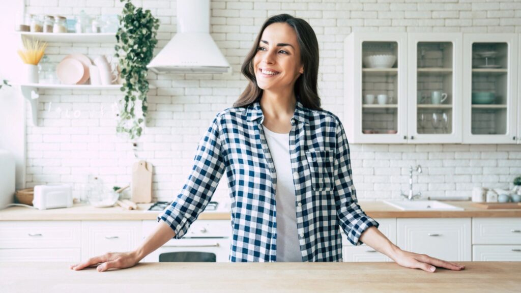 Young beautiful modern woman stands near table on kitchen at home