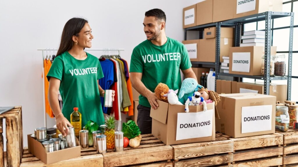 Young latin volunteer couple smiling happy working at charity center.