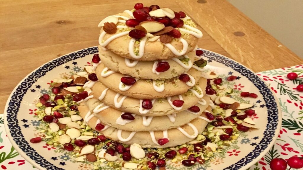 A small kransekake, decorated with nuts and fruit as well as the traditional white glaze.