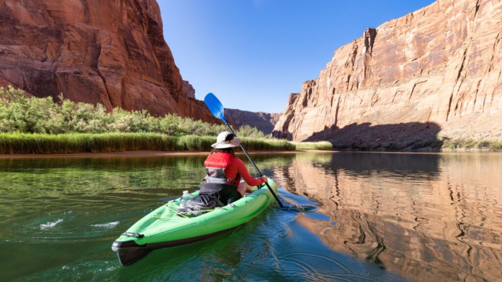 Adventurous Woman on a Kayak paddling in Colorado River. Glen Canyon, Arizona, United States of America. American Mountain Nature Landscape Background.