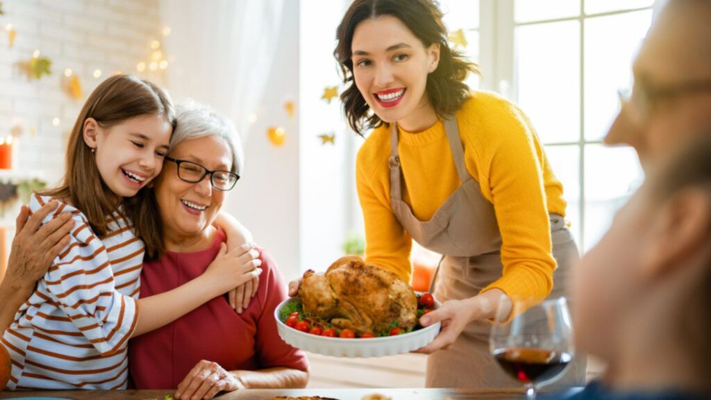 Family sitting at the table and celebrating holiday with a turkey. Grandparents, mother and children. Traditional dinner