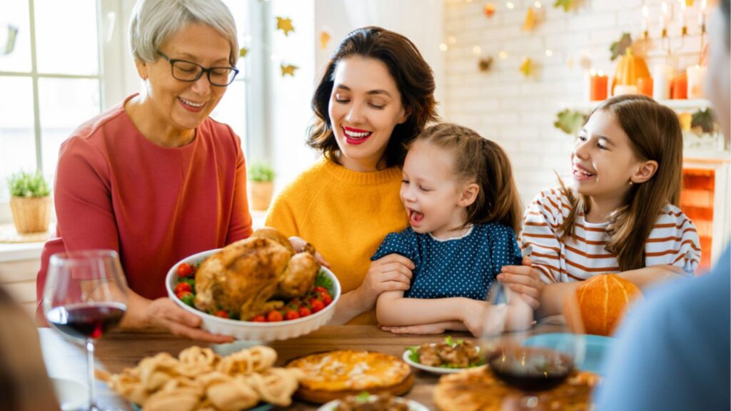 Happy Thanksgiving Day! Autumn feast. Family sitting at the table and celebrating holiday. Grandparents, mother, father and children