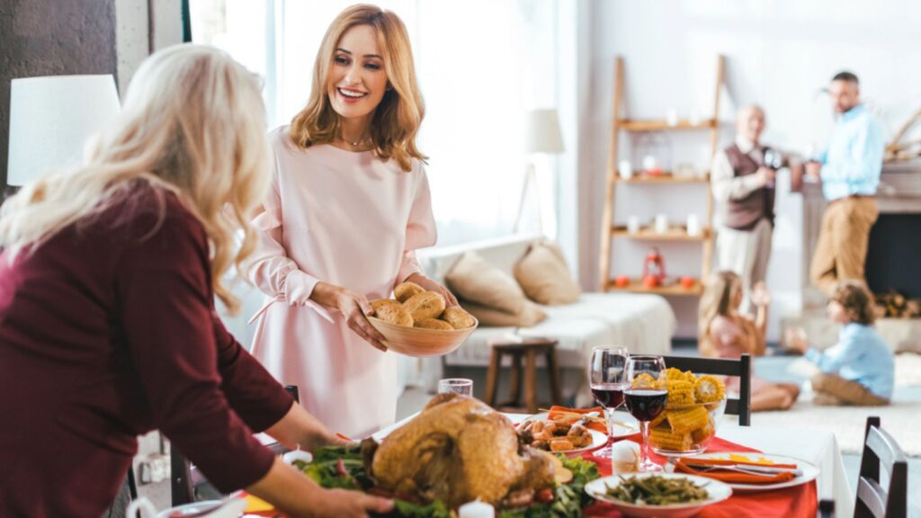 Happy young and senior women serving thanksgiving day table