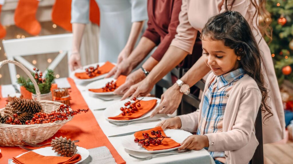 Little girl decorating christmas table with women