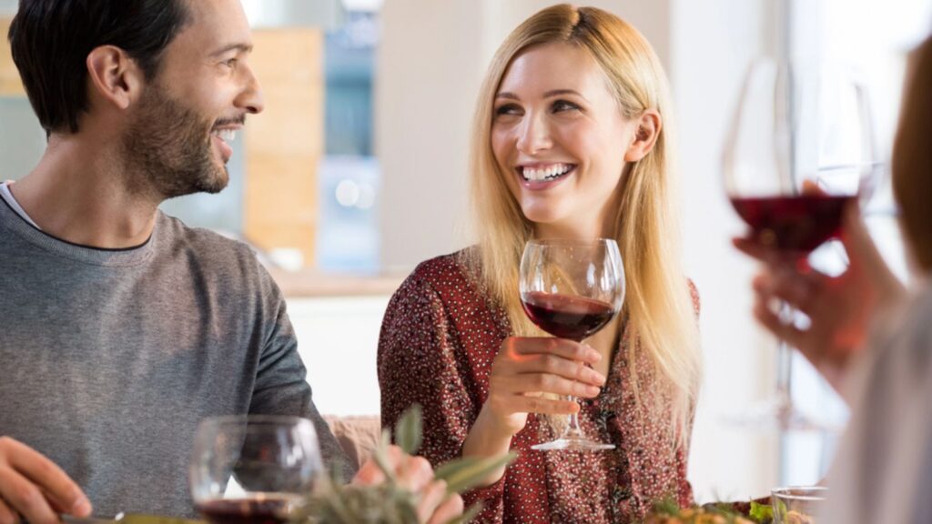 Portrait of a happy friends reunion. Young couples enjoying wine and drinks. Couple enjoying lunch with family at home.