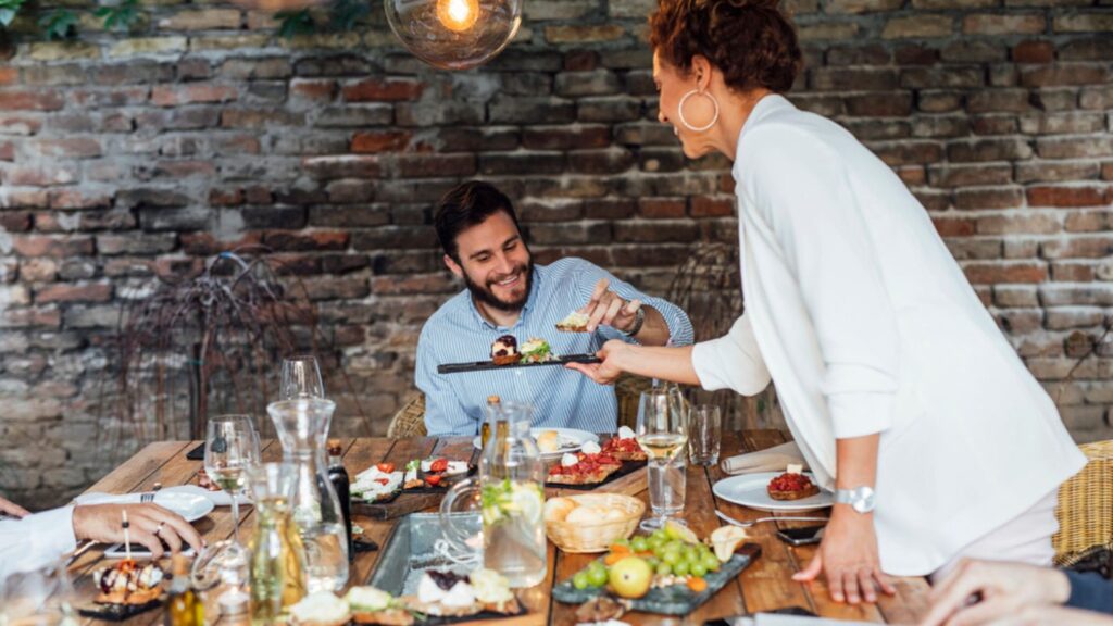 Pretty Elegant caucasian Woman Dinner Party Host Serving Food to Her Friend at outdoor