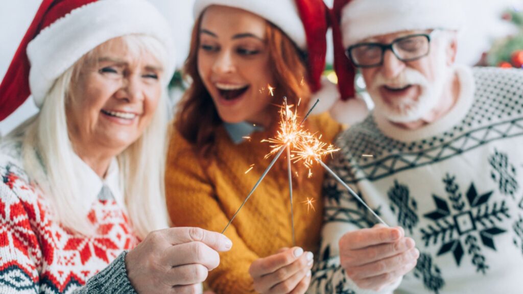 Selective focus of senior couple with daughter lighting sparklers on Christmas celebration