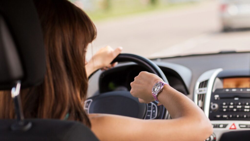 Transportation and vehicle concept- woman driving a car and looking at the watch