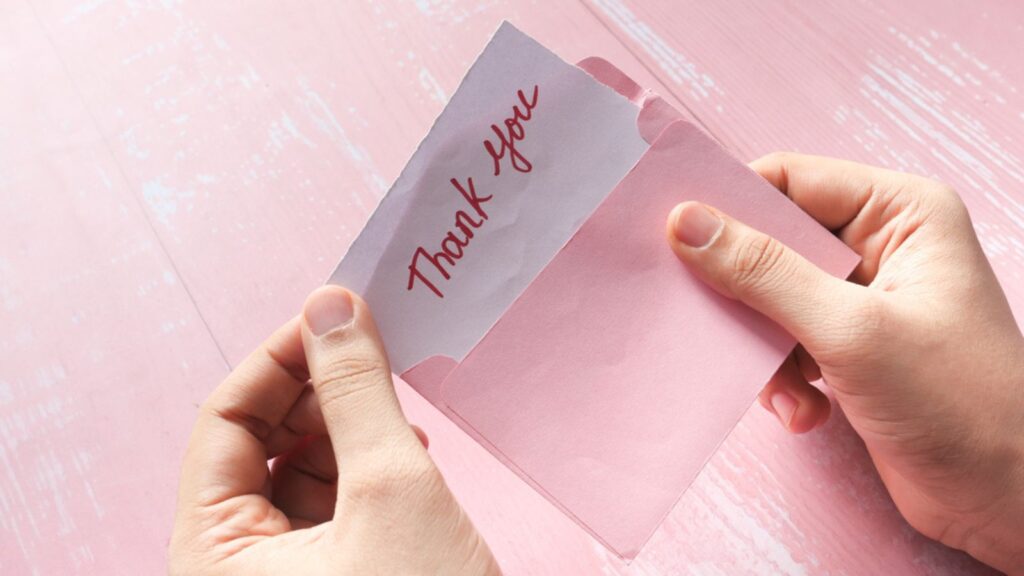 Womens hand holding thank you letter , top down