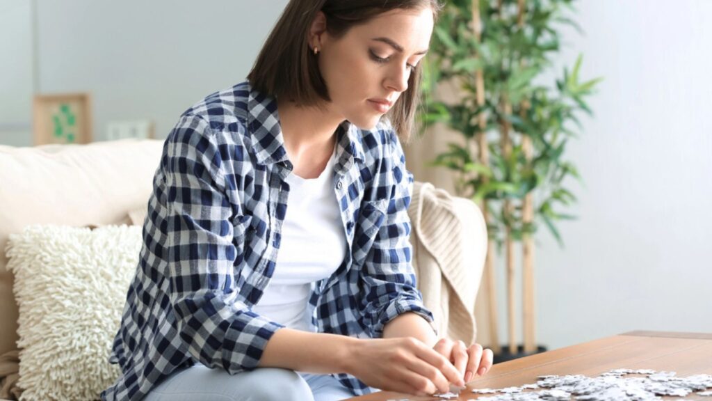 Young woman doing jigsaw puzzle at home