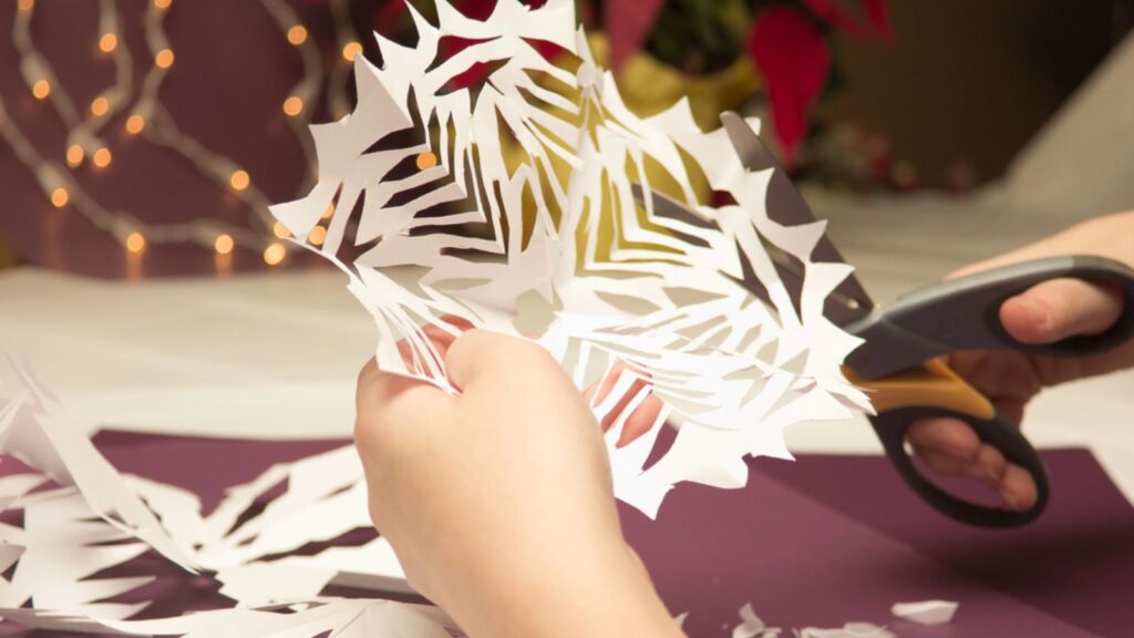woman cutting and making Paper Snowflakes