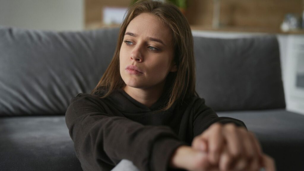 Caucasian sad woman sitting on the floor and looking away
