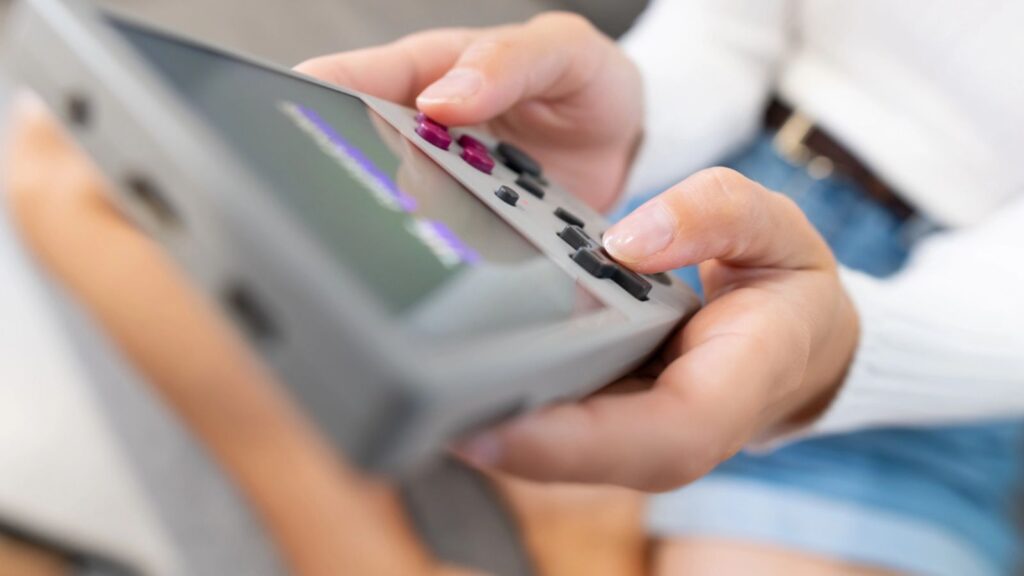 Close-up of female hands of young Caucasian woman holding retro video game console. Girl playing retro games on portable game console.